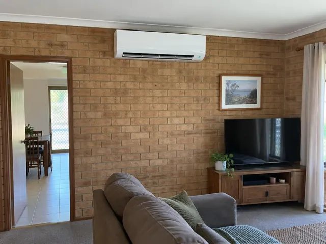 Clean split system mounted high on a brick living room wall with louvre open in Davoren Park