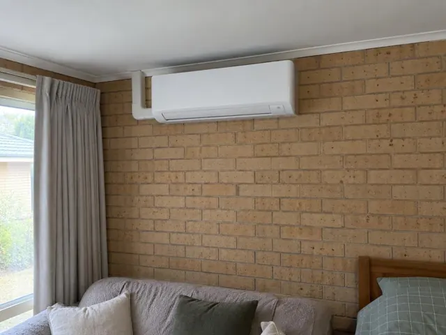 Split system indoor unit on a brick bedroom wall above a bed in Andrews Farm